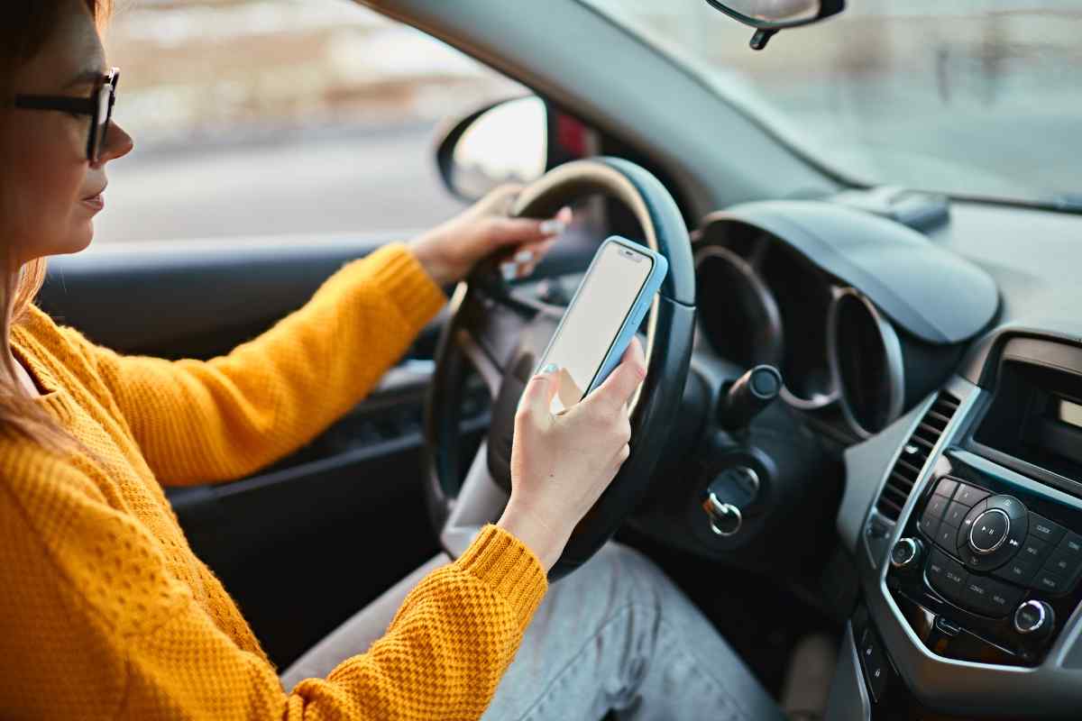 una persona guarda lo smartphone mentre guida